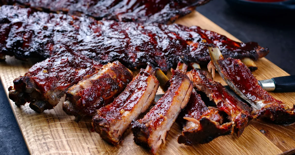 A rack of smoked ribs sliced into individual bones on a cutting board