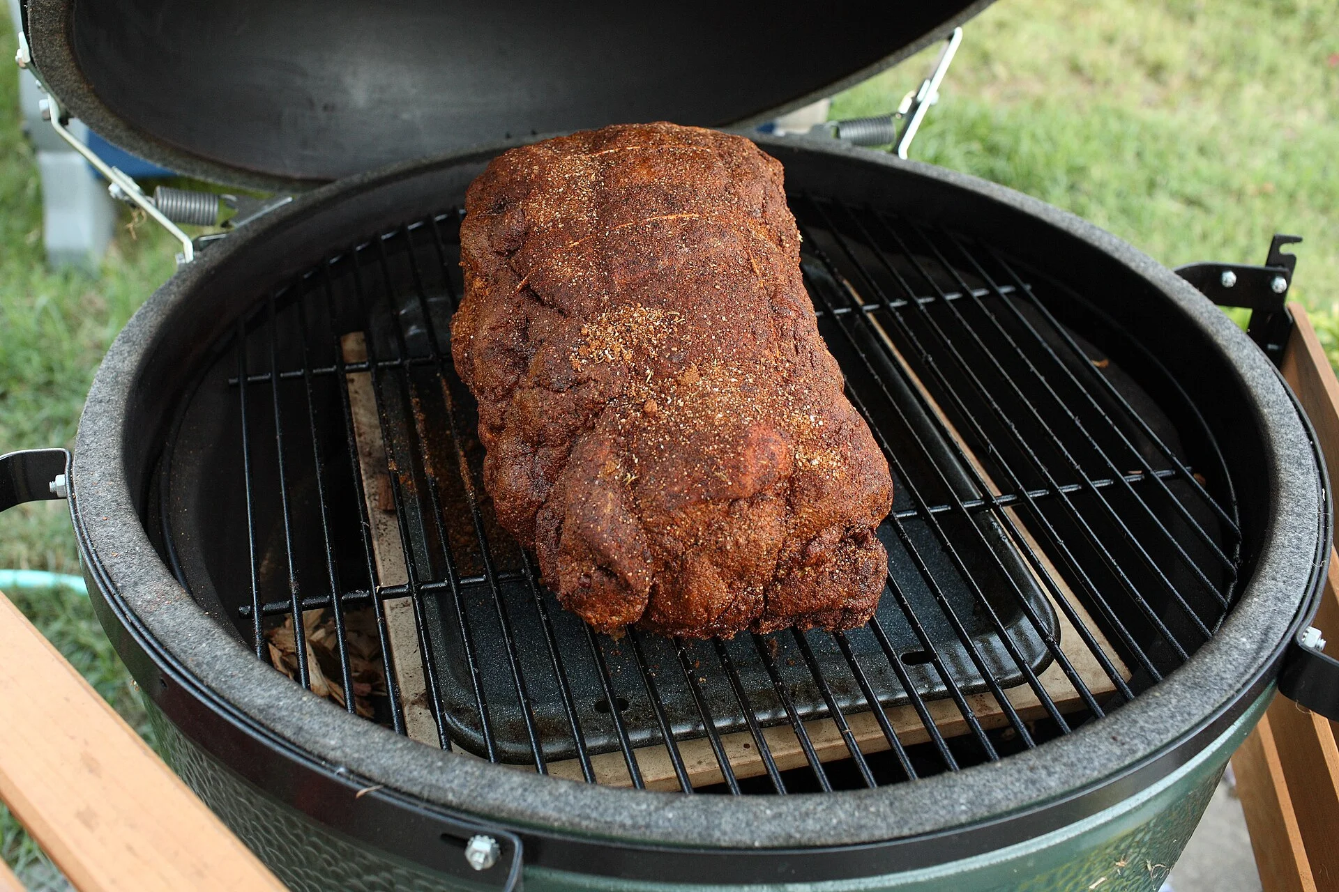 A fork pulling a smoked pork shoulder apart into glossy strands, the interior moist and glistening under warm light