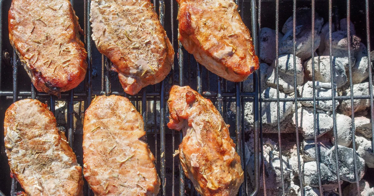 Pieces of meat cooking on a barbecue grill grate