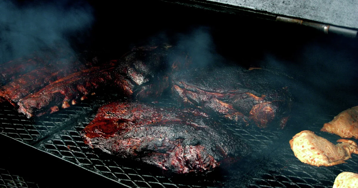 Meat cooking over a live fire inside a smoker