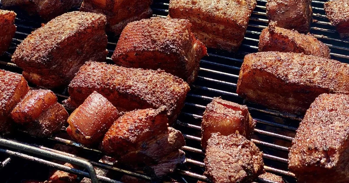 Cubed pork belly cooking on a barbecue grate