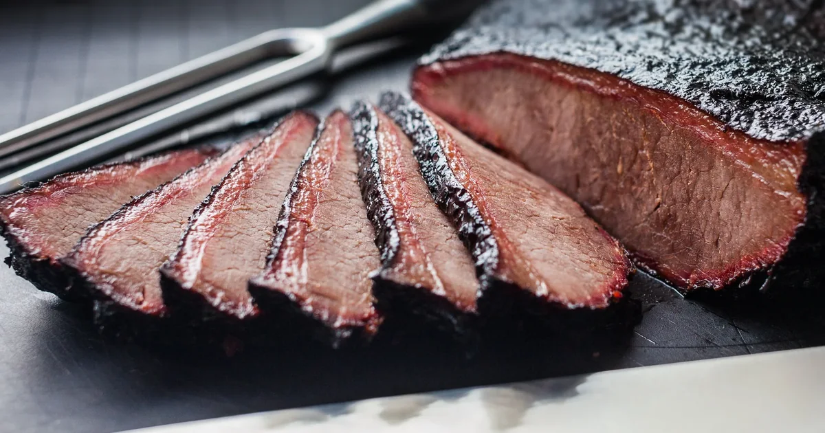 Slices of smoked brisket showing a pink smoke ring beneath the bark